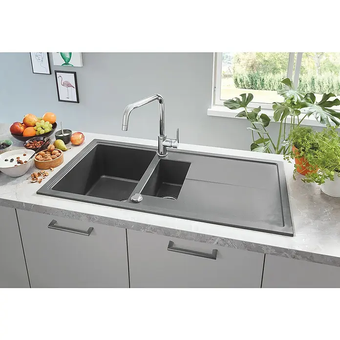 Grohe Eurosmart Cosmopolitan Spültischarmatur 2 - Chrom, Glänzend - Das Bild zeigt eine moderne, graue Küchenspüle mit Abtropffläche und einer stilvollen Armatur, eingebettet in eine helle Küchenarbeitsplatte.