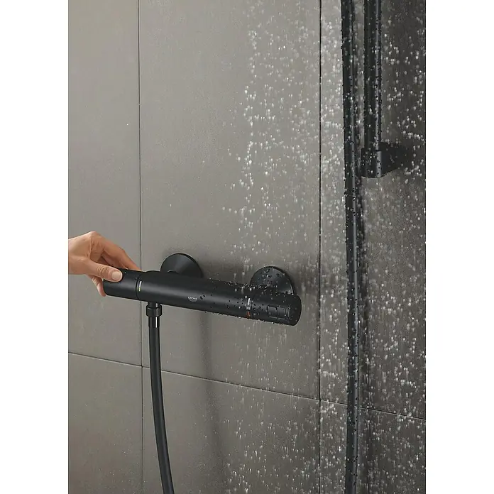 Grohe Start Brausethermostat Precision - Matt, Schwarz - Duscharmatur aus schwarzem Metall mit Wasser, das aus dem Duschkopf fließt und von einer Hand bedient wird.