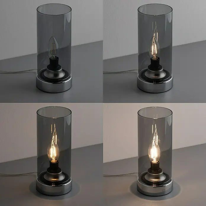 Paulmann Tischleuchte Pinja - 20 W, L x B x H: 11 cm x 11 mm x 24,4 cm, Rauch, Chrom, E14 - Nahaufnahme einer Tischleuchte mit grauem Glaszylinder und dekorativer Glühbirne, die in vier Helligkeitsstufen dargestellt wird.
