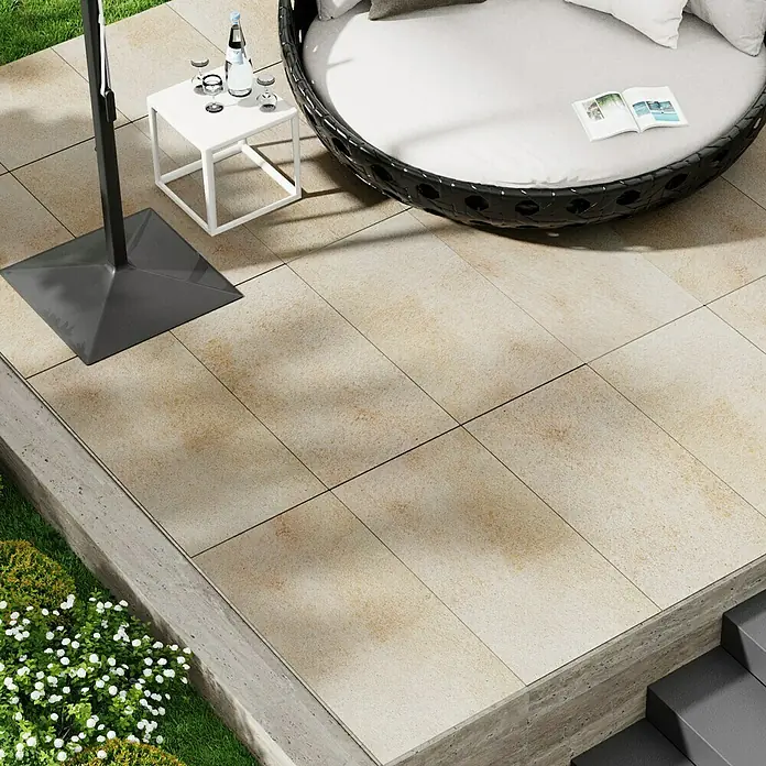 Marazzi Terrassenfliese Esterno 20T Jerusalem Avori50 x 100 x 2 cm, Hellbeige, Matt - Nahaufnahme von rechteckigen Pflastersteinen, die einen entspannenden Außenbereich mit einem runden Liegestuhl und einem Beistelltisch bilden.