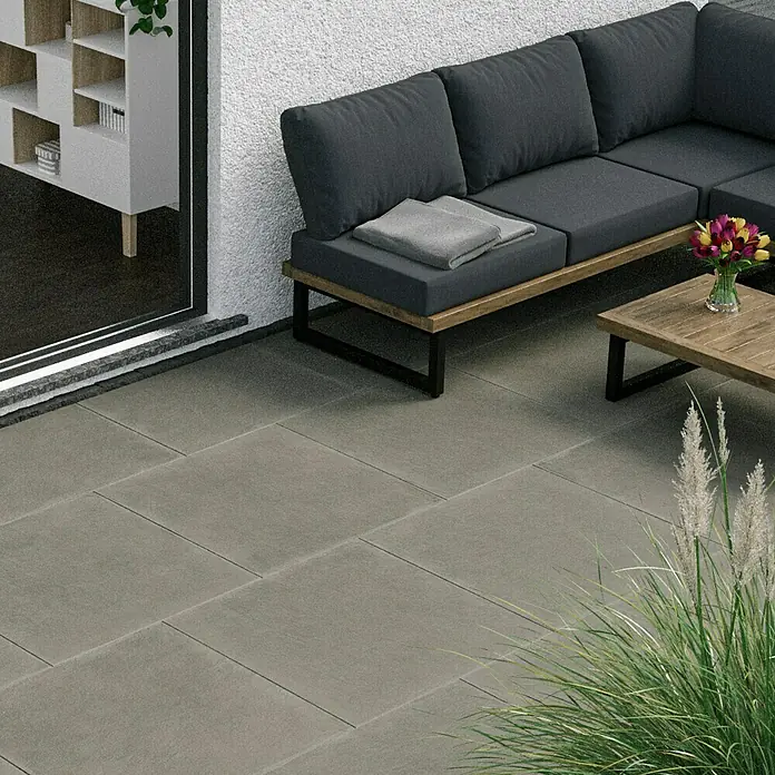 Marazzi Terrassenfliese Esterno 20T Material80 x 80 x 2 cm, Grau, Matt - Bild eines modernen grauen Terrassenbereichs mit grauen Fliesen, einer grauen Couch und einem Holztisch mit Blumen.