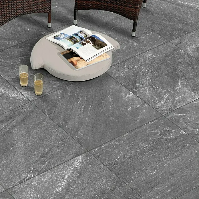 Terrassenfliese Cera 2.0 - 80 x 80 x 2 cm, Quarz Nero, Matt - Aufnahme von grauen Bodenfliesen mit Tisch, Stühlen und Getränken. Die Bodenfliesen verleihen dem Außenbereich eine moderne Note.
