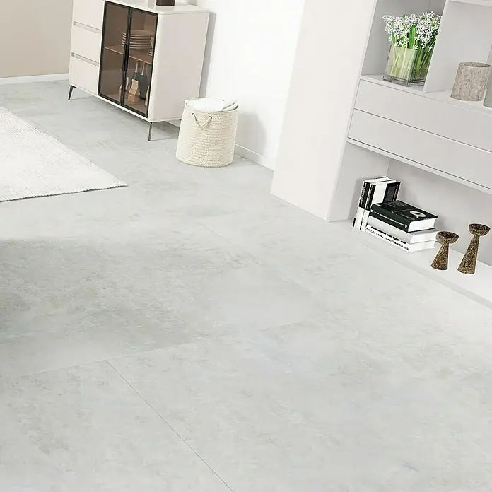 Feinsteinzeugfliese Luna Bianco - 120 x 240 cm, Weiß/Grau, Glänzend - Die Aufnahme zeigt einen hellen Raum mit grauem Fliesenboden. Ein weißes Sideboard und ein offenes Regal mit Deko vervollständigen das Interieur.