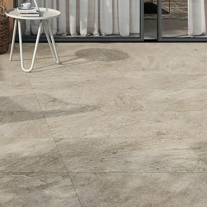Atlas Concorde Solution Regent Terrassenfliese Ivory - 45 x 90 x 2 cm, Beige/Braun, Matt - Eine Nahaufnahme von beigefarbenen Bodenfliesen mit einem Tisch und Vorhängen im Hintergrund.