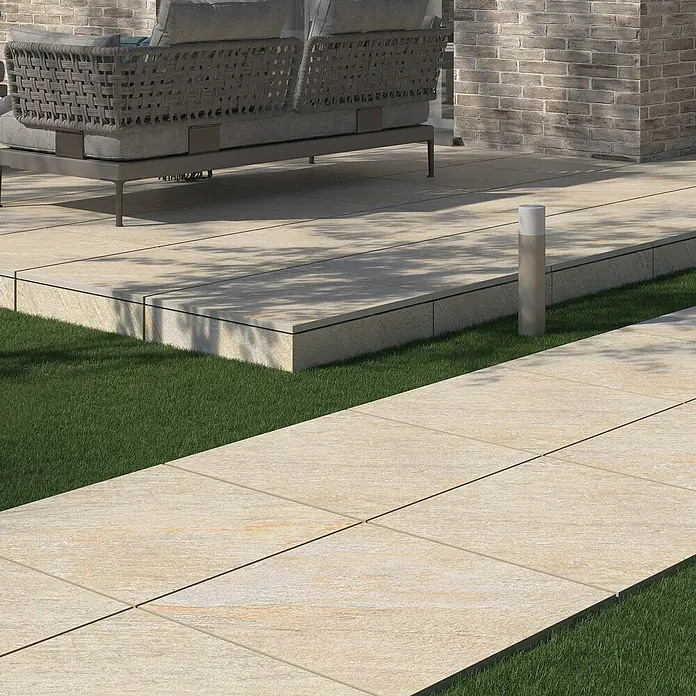 Terrassenfliese Piazza 2.0 - 59,7 x 59,7 x 2 cm, Beige, Matt - Außenaufnahme von Terrassenplatten aus hellem Stein, die einen stilvollen und modernen Gartenweg bilden. Die Platten sind eben und passen gut zum Rasen.