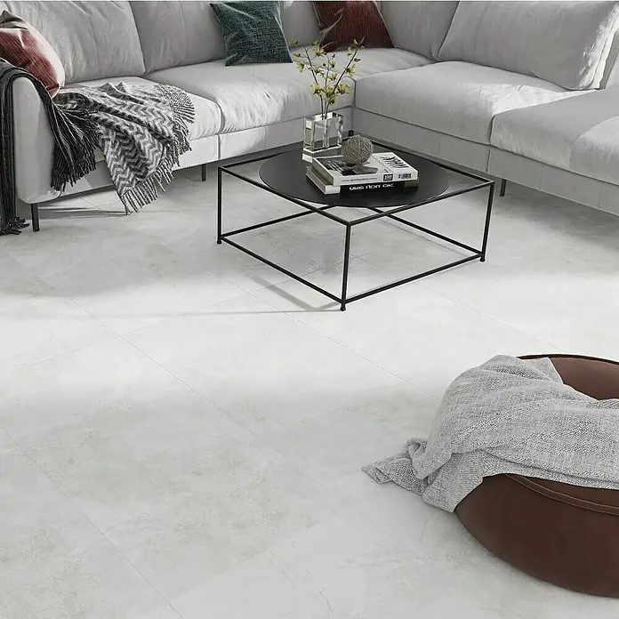 Feinsteinzeugfliese Geo White - 60 x 120 cm, Weiß, Schimmernd - Ein modernes Wohnzimmer mit einem grauen Sofa, einem schwarzen Couchtisch und einem braunen Sitzsack, die auf einem hellen Bodenbelag stehen.