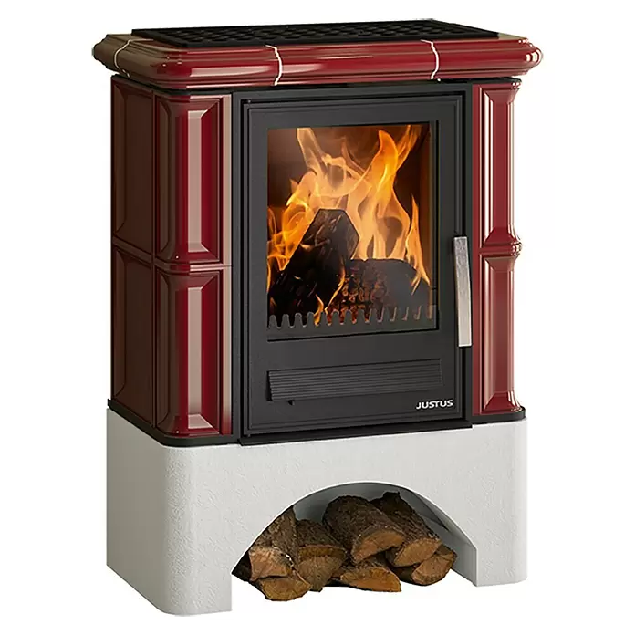 Justus Kaminofen Bavaria - 7 kW, Raumheizvermögen: 144 m³, Material Verkleidung: Keramik, Bordeaux - Roter Kaminofen mit brennenden Holzscheiten und weißem Holzfach.
