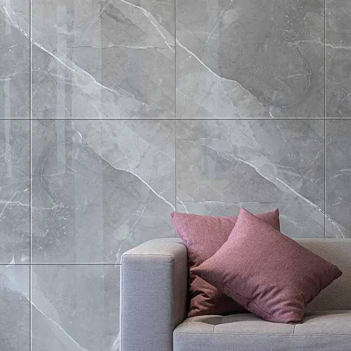 Feinsteinzeugfliese Amani Marble Light - 80 x 80 cm, Grau, Glänzend - Moderne graue Marmorfliesenwand mit dezenten weißen Akzenten, kombiniert mit einem stilvollen grauen Sofa und zwei purpurroten Kissen für Gemütlichkeit.