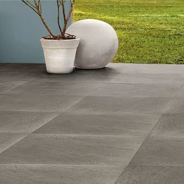 Terrassenfliese Manhattan 2.0 - 60 x 90 x 2 cm, Grau, Matt - Graue Terrassenfliesen mit Topfpflanze und Dekokugel. Die Fliesen verleihen dem Außenbereich ein elegantes und modernes Aussehen.