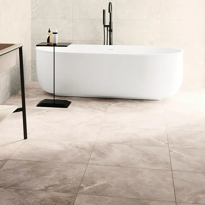 Domicil Feinsteinzeugfliese Stone Art - 60 x 60 cm, Caramel Beige, Matt - Elegantes Badezimmer mit freistehender Badewanne und modernem, schwarzem Armaturen-Design, ergänzt durch einen stilvollen Beistelltisch mit Pflegeprodukten.