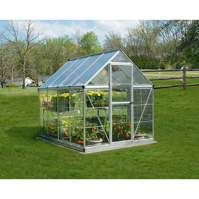 Palram – Canopia Invernadero Hybrid - Medidas ext. (An x Pr): 185 x 248 cm, Plateado, Área: 4,6 m² - Un invernadero de vidrio lleno de plantas y flores se encuentra en la hierba verde, un lugar bonito para cultivar verduras.