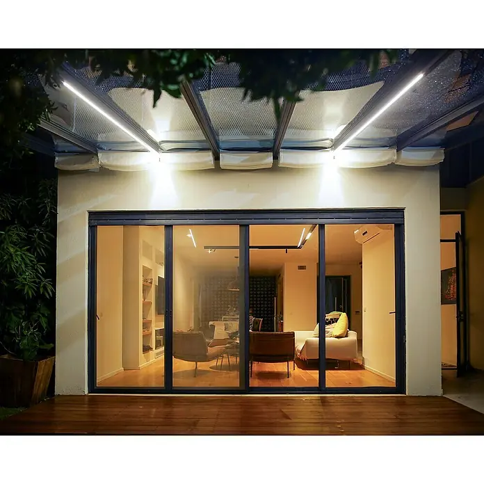 Palram – Canopia LED-Band - 25 W, Neutralweiß, Länge 2,7 m - Modernes Haus mit großen Glasschiebetüren, die einen Blick in ein stilvolles Wohnzimmer ermöglichen. Beleuchteter Terrassenbereich für gemütliche Abende.