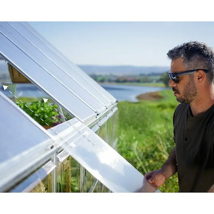 Palram – Canopia Invernadero Balance - Medidas ext. (An x Pr): 304 x 964 cm, 0,7 mm, Plateado - Un hombre instala una cubierta para invernadero. La cubierta es transparente y se está fijando a un marco.