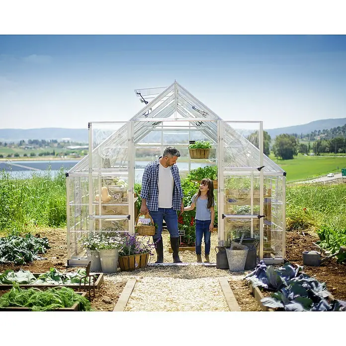 Palram – Canopia Invernadero Balance - Medidas ext. (An x Pr): 304 x 484 cm, 0,7 mm, Plateado - Un invernadero de aluminio con un hombre y una niña entrando al jardín.