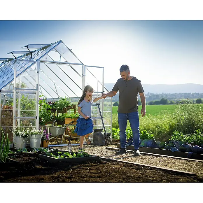 Palram – Canopia Invernadero Balance - Medidas ext. (An x Pr): 304 x 484 cm, 0,7 mm, Plateado - Un invernadero con un padre y su hija haciendo jardinería, rodeado de huertos y exuberante vegetación.