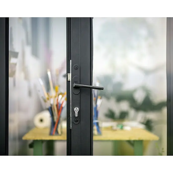 Palram – Canopia Caseta de jardín Copenhaguen - Medidas ext. (An x Pr): 351 x 287 cm, Plástico, Negro - Primer plano de una puerta negra con manija y cerradura, que ofrece una vista de un interior brillante y borroso con una mesa y material de arte.