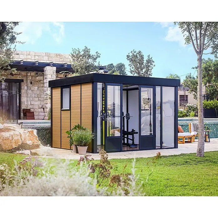 Palram – Canopia Caseta de jardín Copenhaguen - Medidas ext. (An x Pr): 351 x 287 cm, Plástico, Negro - Un gimnasio de jardín moderno con fachada de vidrio y revestimiento de madera, enclavado en un exuberante paisaje de jardín verde.
