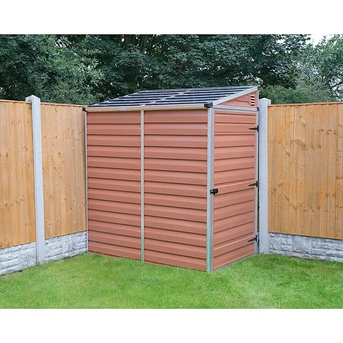 Palram – Canopia Caseta de jardín Skylight - Medidas ext. (An x Pr): 117 x 176 cm, Plástico, Ámbar - Un cobertizo de jardín de metal marrón claro con techo inclinado, situado junto a una valla de madera y césped verde.