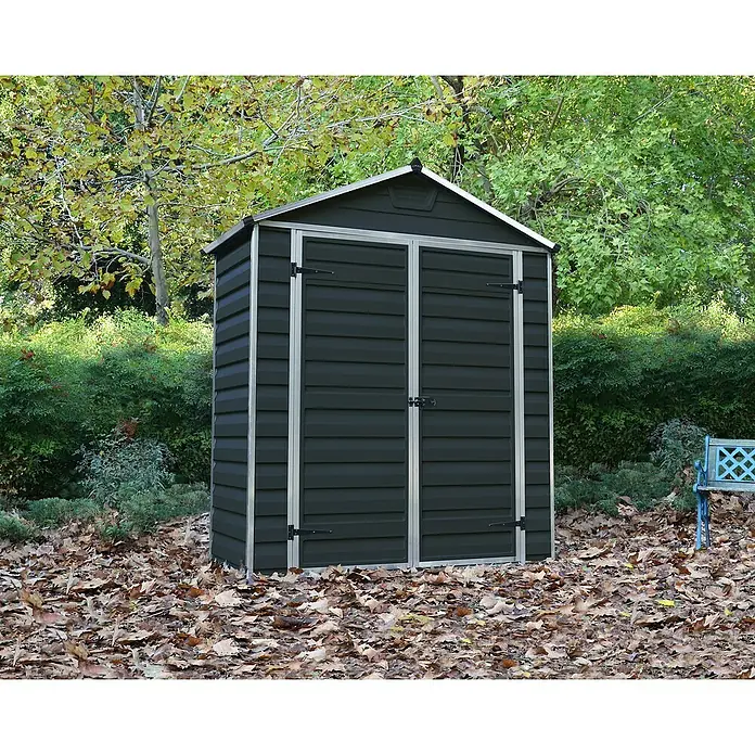 Palram – Canopia Caseta de jardín Skylight - Medidas ext. (An x Pr): 185 x 90 cm, Plástico, Antracita - Caseta de jardín de plástico oscuro con puerta doble y marco gris plateado, rodeada de follaje otoñal.