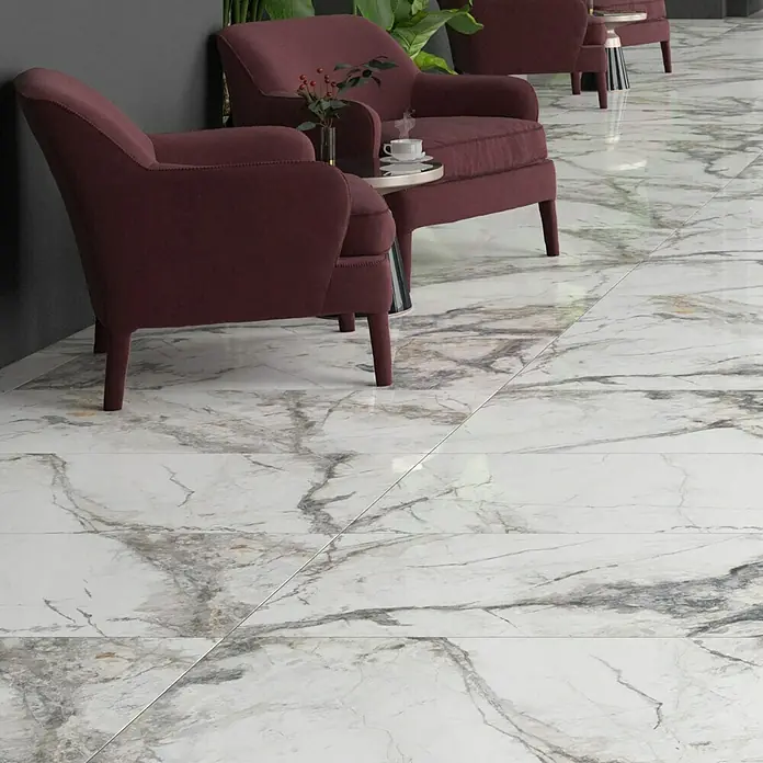 Feinsteinzeugfliese Marble Visage - 60 x 120 cm, Weiß/Grau, Glänzend - Nahaufnahme von eleganten Marmorfliesen mit grauen Adern, die einen luxuriösen Bodenbelag bilden, ergänzt durch stilvolle Sessel im Hintergrund.