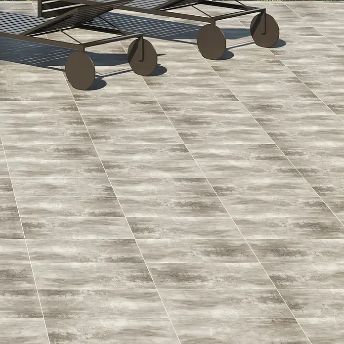 Feinsteinzeugfliese Portland Ceniza - 44 x 66 cm, Grau, Matt - Bild von rechteckigen Pflastersteinen mit verschwommenem grauem Muster, verlegt auf einer sonnigen Terrasse mit Liegestühlen.