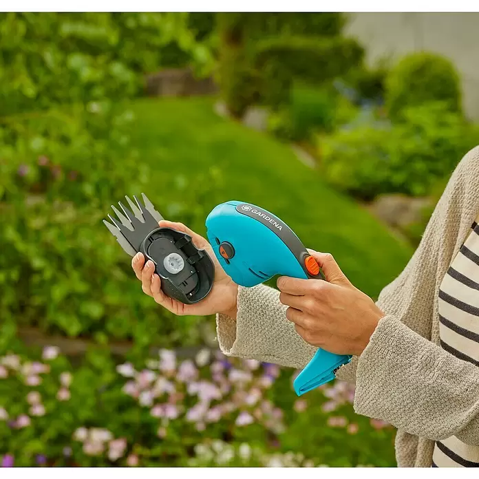 Gardena Power for All 18V Akku-Gras- & Strauchschere 20/18V P4A - 18 V, Li-Ionen, 1 Akku - Eine Person hält eine blaue Gardena Handschere und ihren separaten Klingenaufsatz, was die Modularität des Werkzeugs hervorhebt.