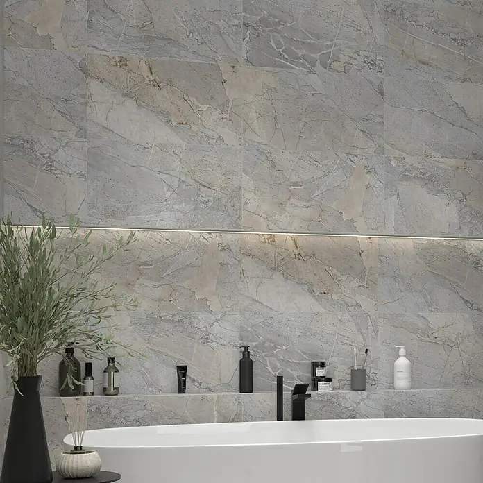 Feinsteinzeugfliese Side - 30 x 60 cm, Grau, Matt - Elegantes Badezimmer mit Marmorfliesen, einer weißen Badewanne und stilvollen Badezimmerartikeln auf einem Regal. Die Beleuchtung sorgt für ein angenehmes Ambiente.