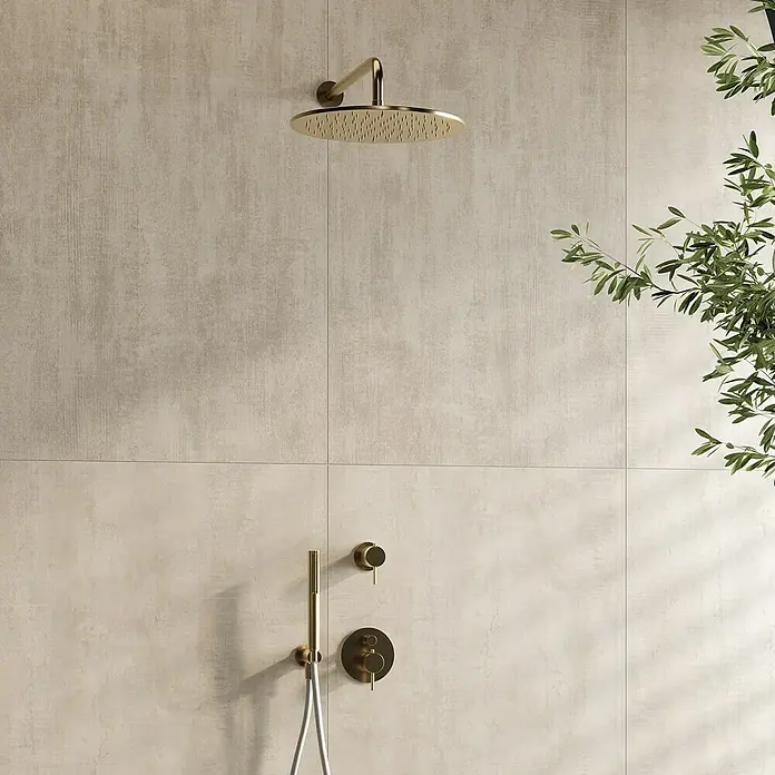 Atlas Concorde Solution Yorkshire Feinsteinzeugfliese Almond - 60 x 120 cm, Beige, Matt - Nahaufnahme eines modernen Badezimmers mit goldenen Armaturen, bestehend aus einer Kopfbrause und einem Handbrause-Set vor beigen Fliesen.