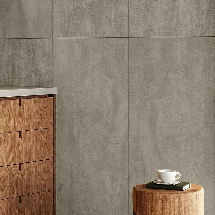 Atlas Concorde Solution Yorkshire Feinsteinzeugfliese Ash - 60 x 120 cm, Grau, Matt - Detailaufnahme einer grauen Zementfliesenwand, ergänzt durch eine Holzkommode und einen Beistelltisch mit Kaffeetasse.