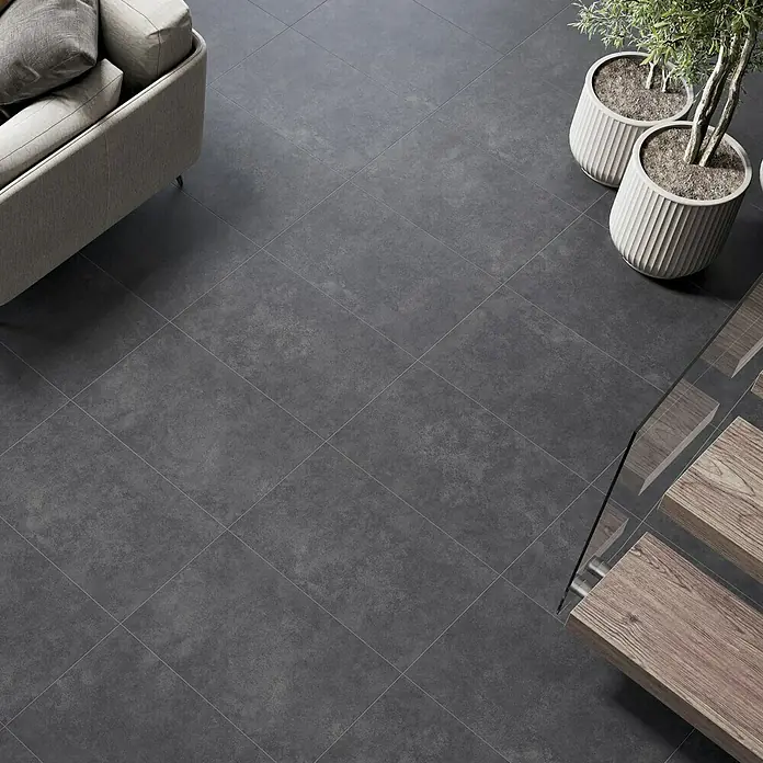 Feinsteinzeugfliese Classico Nero - 44 x 66 cm, Schwarz, Matt - Blick von oben auf einen Raum mit eleganten, quadratischen, dunkelgrauen Fliesen, die eine moderne und stilvolle Atmosphäre schaffen.