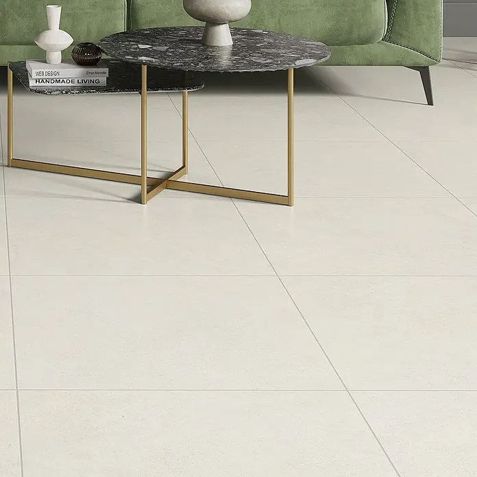 Feinsteinzeugfliese Big Ivory - 60 x 60 cm, Hellbeige, Matt - Ein modernes Wohnzimmer mit einem stilvollen Couchtisch und einem bequemen grünen Sofa auf einem hellen Fliesenboden.