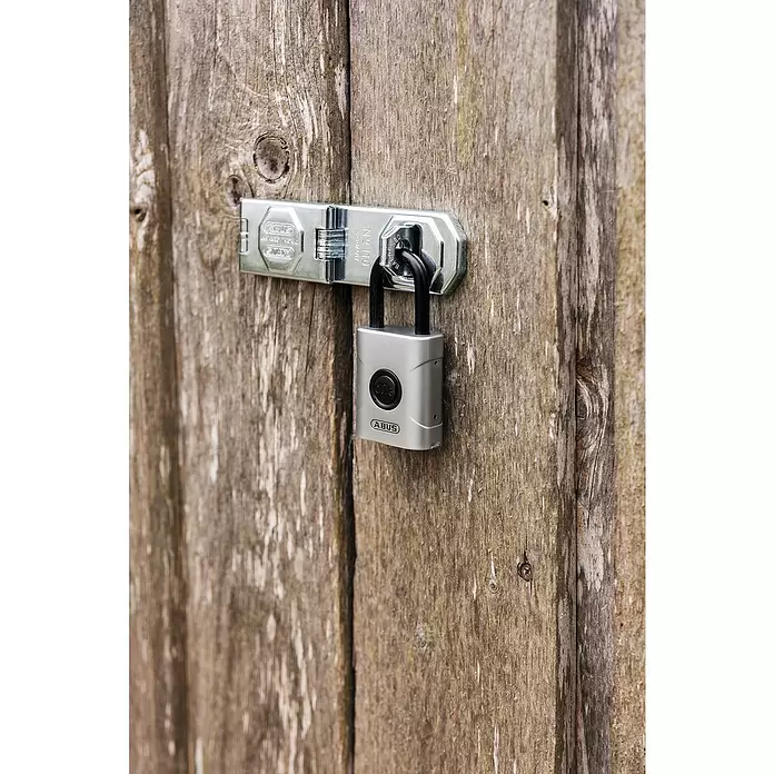 Abus Vorhängeschloss EVEROX 61/50 - Silber, 23 x 50 x 95 mm - Silbernes ABUS Vorhängeschloss mit schwarzem Bügel an einem Metallriegel auf verwitterter Holztür.