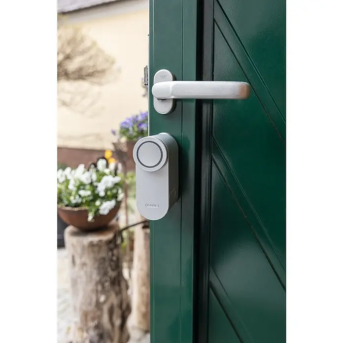 Abus Elektronisches Türschloss LOXERIS CFA4100 S - Bedienung: Über App, Geeignet für: Türen, Silber - Nahaufnahme eines ABUS Smart Locks an einer grünen Tür mit Beschlägen.