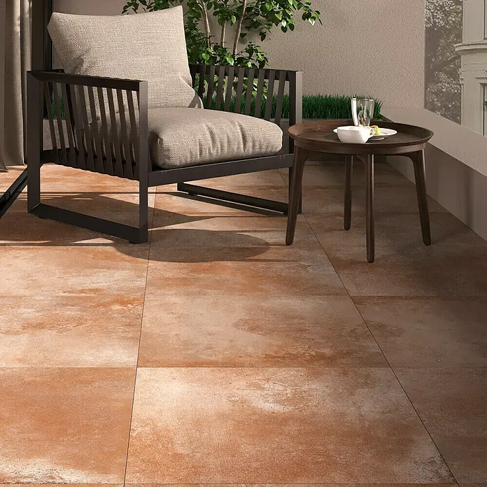 Terrassenfliese Neapel 2.0 - 60 x 60 x 2 cm, Cotto, Matt - Terracotta-farbene Bodenfliesen auf einem Balkon mit Stuhl und Tisch, die ein warmes und stilvolles Ambiente schaffen.