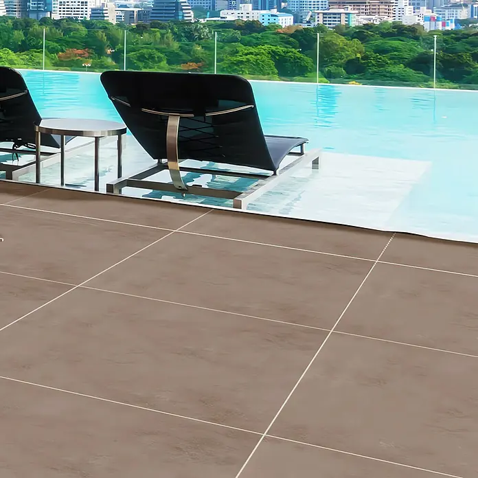 Terrassenfliese Modena - 100 x 100 x 2 cm, Taupe, Matt - Blick auf braune Bodenfliesen im Außenbereich, ergänzt durch moderne Liegestühle und einen Infinity-Pool, der ein luxuriöses Ambiente schafft.