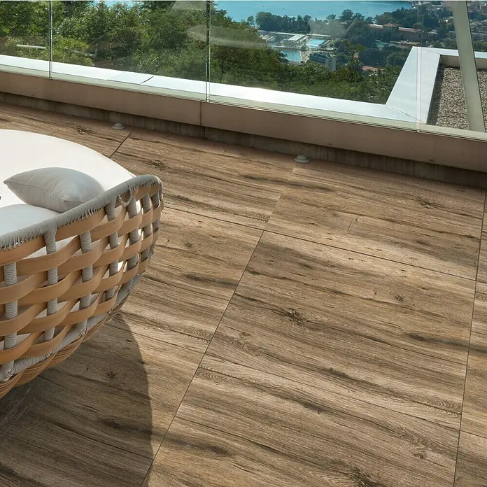Terrassenfliese Strobus - 60 x 60 x 2 cm, Oak/Braun, Matt - Terrassenansicht mit Holzfliesen und einem eleganten runden Sofa mit Kissen, das zum Entspannen im Freien einlädt.