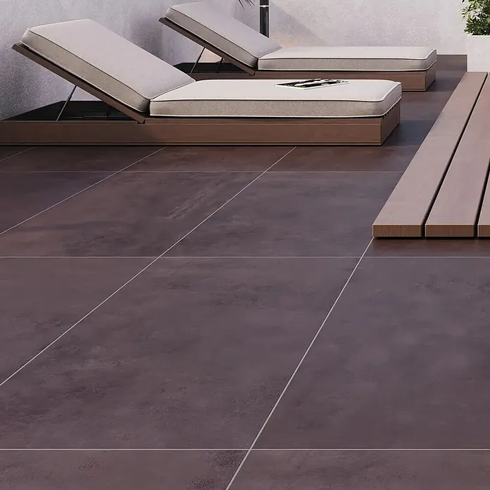 Terrassenfliese Modena - 60 x 120 x 2 cm, Chocolate/Braun, Matt - Das Bild zeigt eine moderne Terrasse mit dunklen Fliesen, zwei Liegen und einem Holzdeck. Die Fliesen verleihen dem Außenbereich ein elegantes Aussehen.