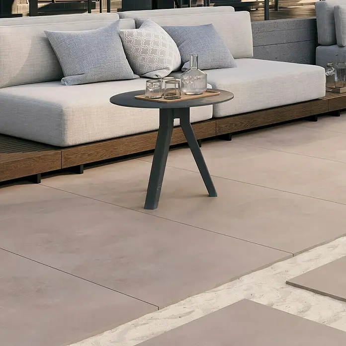 Terrassenfliese Modena - 80 x 80 x 2 cm, Mud/Beigegrau, Matt - Ein stilvoller runder Beistelltisch in Grau mit Getränken darauf, passend zu den modernen Gartenmöbeln im Hintergrund.