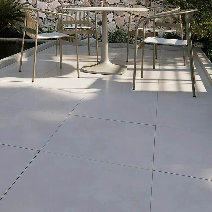 Terrassenfliese Modena - 60 x 60 x 2 cm, Dusty/Grau, Matt - Ein grauer Terrassenbereich mit quadratischen Fliesen, einem runden Tisch und vier Stühlen im Freien, der ein elegantes und modernes Design bietet.