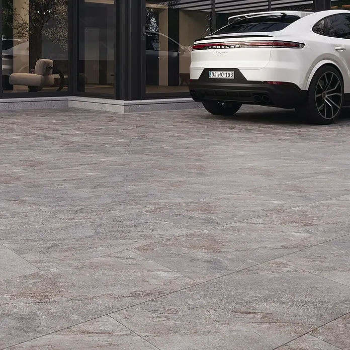 Terrassenfliese Nevada - 40 x 80 x 2 cm, Braun, Matt - Außenaufnahme von Steinpflaster, ideal für Terrassen und Gärten, kombiniert mit einem eleganten weißen Porsche im Hintergrund.