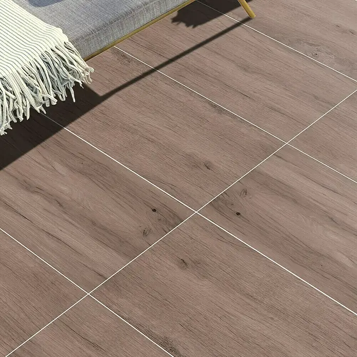 Terrassenfliese Timbertwo - 40 x 120 x 2 cm, Marone/Braun, Matt - Nahaufnahme von Holzbodenfliesen mit einem grauen Sofa und einer Decke, die ein warmes und modernes Ambiente schaffen.