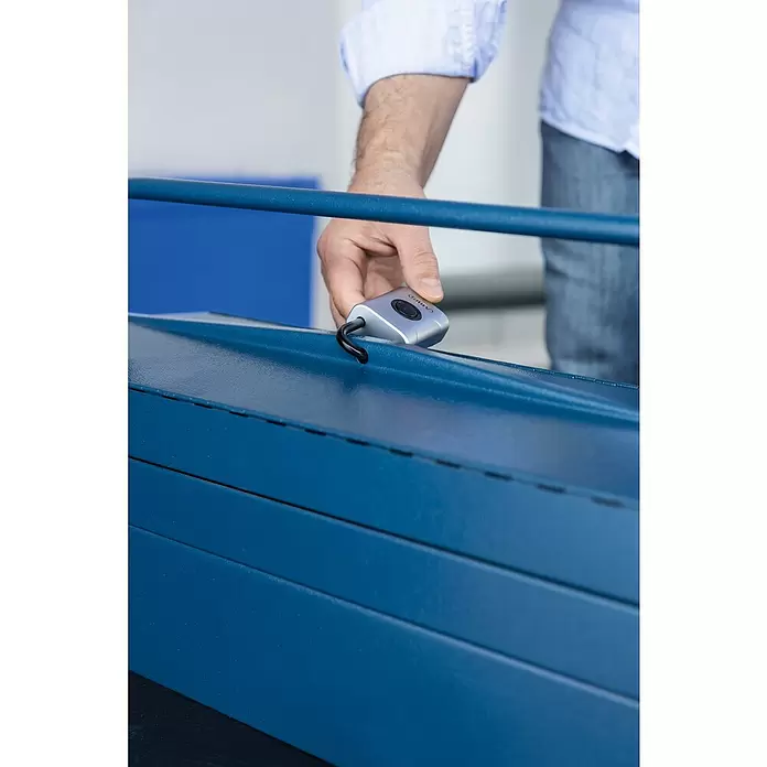 Abus Vorhängeschloss EVEROX 61/45 - SIlber, 23 x 45 x 95 mm - Eine Hand bedient ein silbernes CAIBO-Steuergerät auf einem strukturierten blauen Rollladen, mit schwarzem Knopf und Kabel.