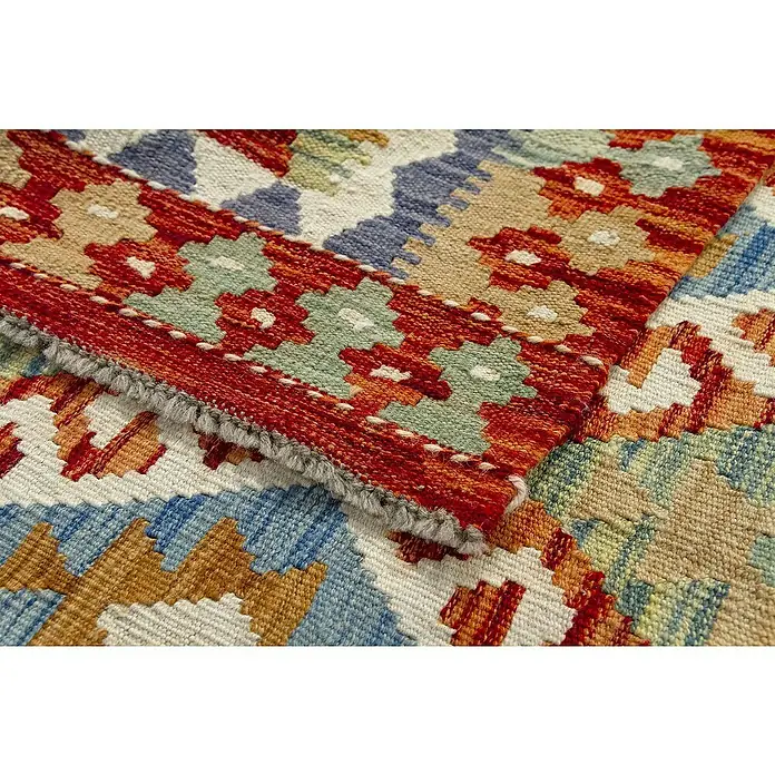 Alfombra de pelo corto Kilim Herat - Multicolor, 150 x 100 cm, 100% lana - Primer plano de una vibrante alfombra kilim con patrones geométricos en rojo, azul, beige y verde. La textura y el fleco son claramente visibles.