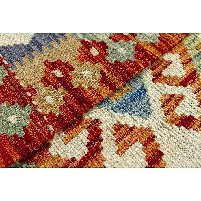 Alfombra de pelo corto Kilim Herat - Multicolor, 150 x 100 cm, 100% lana - Primer plano de una alfombra kelim detallada con patrones geométricos en tonos de rojo, azul y beige. La textura es claramente visible.
