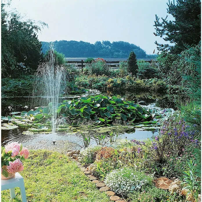 Ubbink Wasserspielpumpe ProLine 1400 Eco - Fördermenge pro Std.: 1.400 l - Teichfontäne umgeben von Seerosen und üppiger Vegetation. Ein ruhiger Garten, der zum Verweilen einlädt.