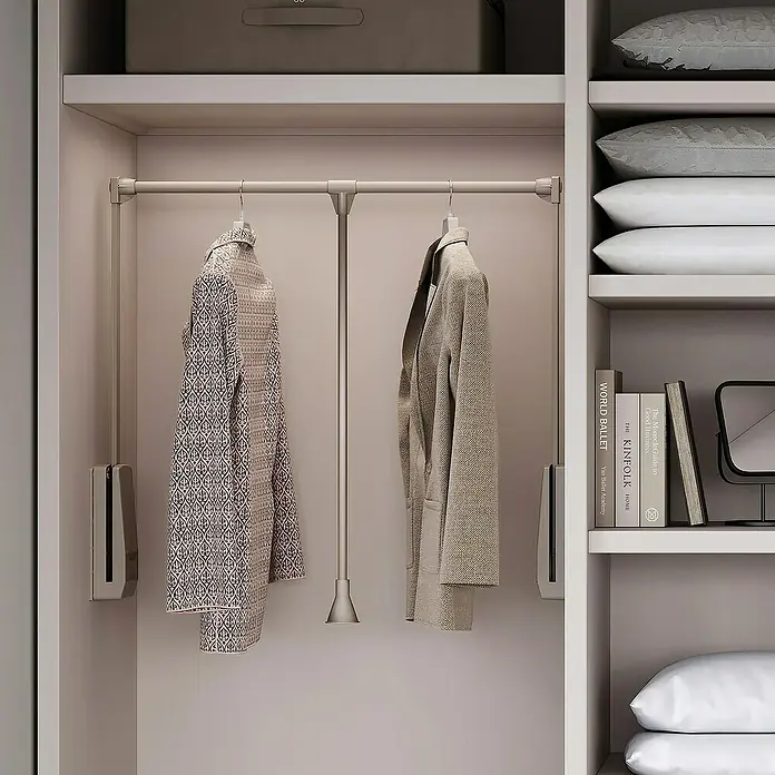 Emuca Kleiderstange Hang - Breitenverstellung: 830 mm - 1.150 mm, Grau - Kleiderschrank mit zwei hängenden Kleidungsstücken an einer Kleiderstange und Regalen mit Kissen und Büchern.