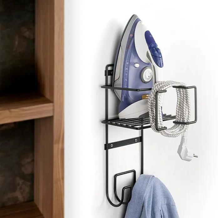 Emuca Wandendhalter für Bügeleisen und Bügelbrett - L x B x H: 200 x 200 x 380 mm, Anthrazitgrau - Ein blaues Bügeleisen und das Kabel sind an einer schwarzen Wandhalterung befestigt, daneben ein Holzregal.