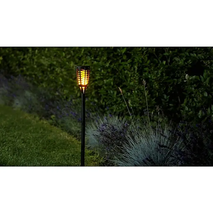 BAUHAUS Solar-Erdspieß Fackel Flame - Schwarz - Diese Aufnahme zeigt eine Solar-Gartenfackel, die warmes Licht inmitten eines grünen Gartens ausstrahlt. Perfekt für stimmungsvolle Abende.