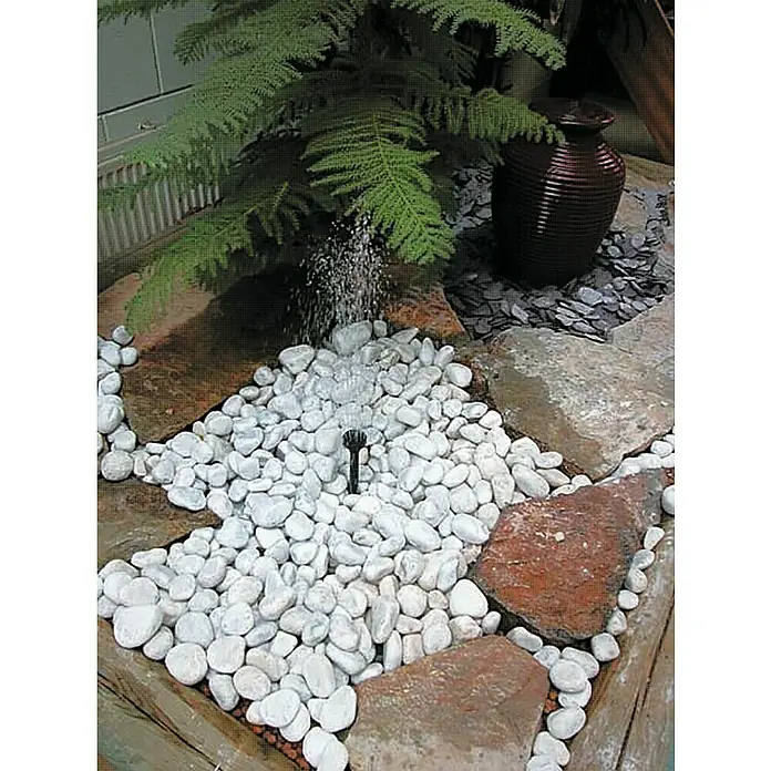 Ubbink Wasserspielpumpe ProLine 3000 Eco - Fördermenge pro Std.: 2.510 l - Wasserspiel mit weißen Kieselsteinen und einer dekorativen Vase, umgeben von Grünpflanzen für eine entspannende Atmosphäre im Garten.