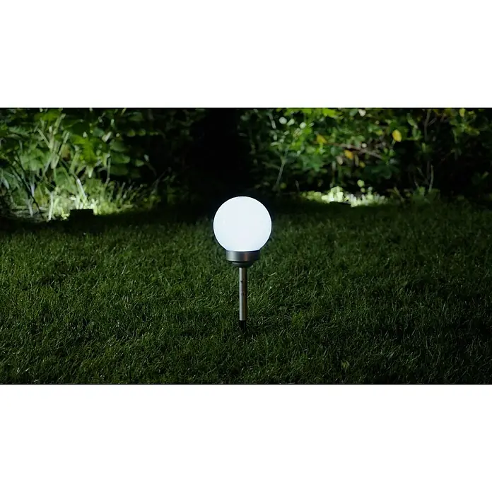 BAUHAUS Solar-Dekoleuchte Fara - Durchmesser: 15 cm, Höhe: 47,5 cm, LED - Eine leuchtende Gartenkugel auf einem Rasen in der Nacht, die Atmosphäre schafft. Die Solarleuchte ist ein dekoratives Element im Garten.